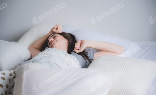 Preview: Pretty young woman relaxing on bed in modern apartment smiling after wake up in the morning at home