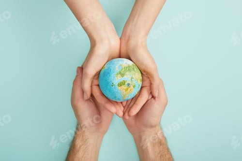 Preview: top view of man and woman holding planet model on turquoise background, earth day concept