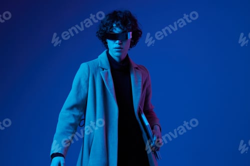 Preview: Portrait of a male hacker with a laptop and futuristic glasses in blue light, Blue Perennial color