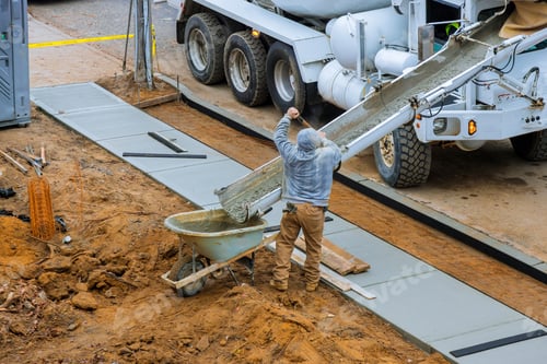 Preview: Construction worker pour cement for sidewalk in concrete works with mixer truck with wheelbarrow at