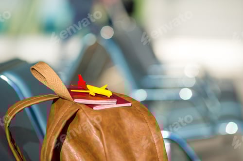 Preview: Closeup passports and airplane model on backpack at airport