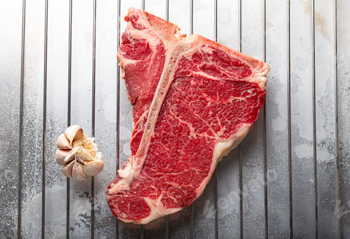 Preview: Raw beef T-bone steak on aluminum tray from above