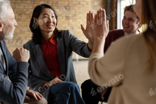 Preview: Asian businesswoman giving high five to colleague during business meeting