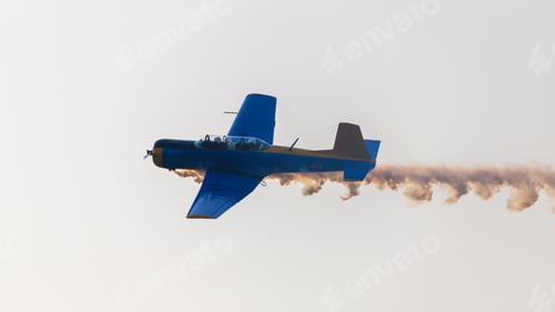 Preview: Aircraft performing an aerobatic maneuver with a smoke trail against a clear sky