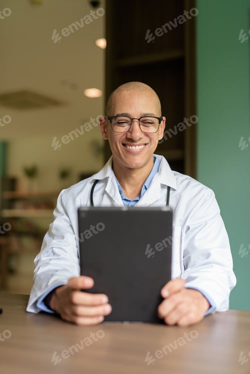 Preview: Doctor Sitting Indoors in Clinic or Hospital Area Library with Stethoscope using Tablet Computer