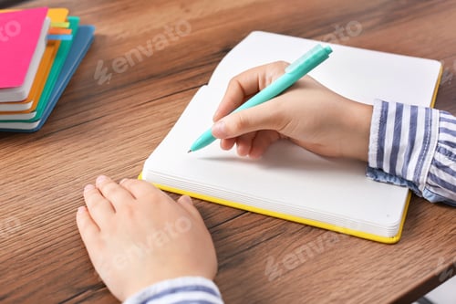 Preview: Woman writing in notebook at wooden table, closeup