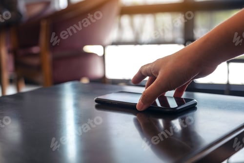 Preview: A hand grabbing and picking up mobile phone on the table