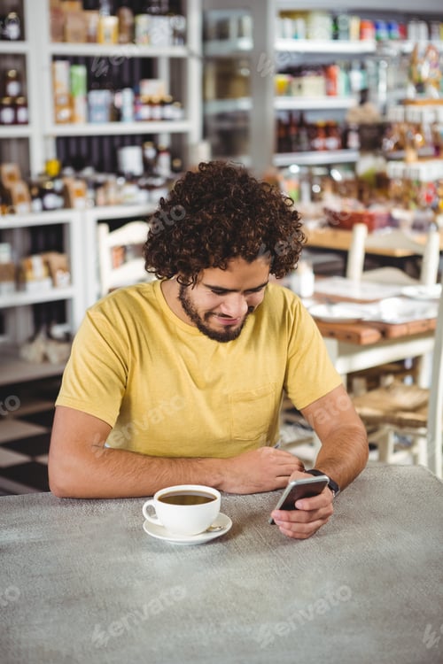 Preview: Man Using Mobile Phone In Cafeteria