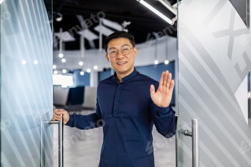 Preview: A young Asian architect, designer, engineer stands in the doorway of a modern office, greets