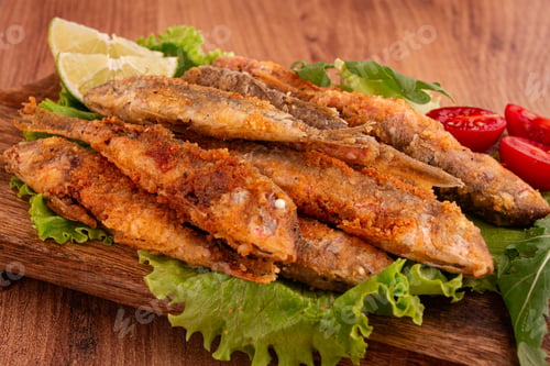 Preview: Fried crispy red mullet fish, on a wooden chopping board, with lime, no people,