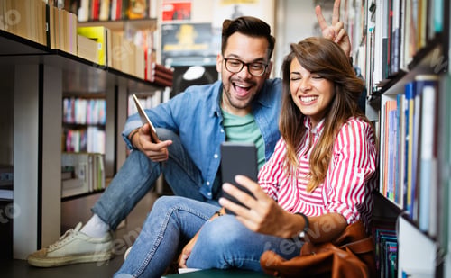Preview: Happy beautiful hipster love student couple taking a selfie in school library