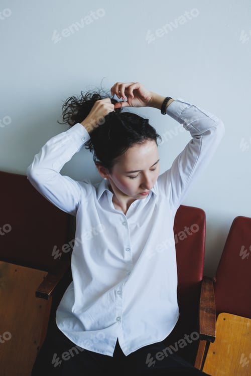 Preview: Candid Portrait of a Woman Skillfully Tying Her Hair in a Minimalist and Serene Setting