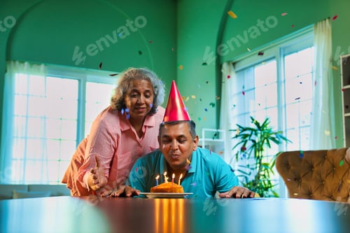 Preview: Husband's birthday celebration with cake and clapping wife in cozy home setting filled with joy