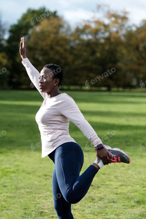 Preview: Serious and motivated black mature woman stretching outdoors.