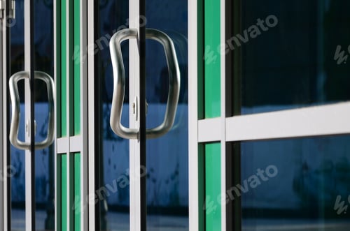 Preview: Chrome door handle and glass of modern aluminium door outside the office building