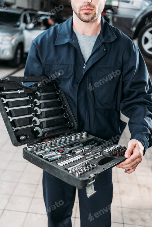 Preview: cropped view of workman in uniform holding tool case