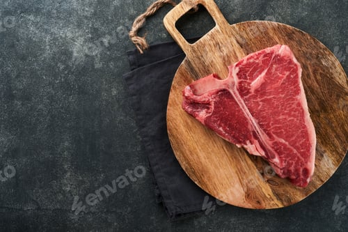 Preview: Thick Raw T-Bone Steak. Dry-aged Raw T-bone or porterhouse beef meat Steak on cutting boar with herb