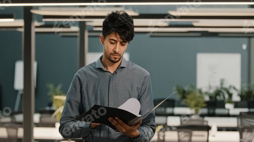 Preview: Young Man Reviews Documents in Modern Office