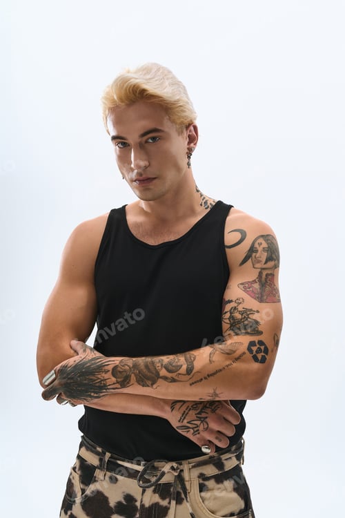 Preview: Stylish young man showcases modern fashion with tattoos in a minimalist studio setting