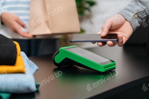 Preview: Man using smartphone for contactless payment in the store