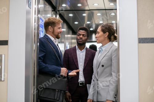 Preview: Young African businessman looking at his interacting colleagues