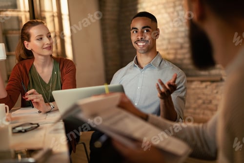 Preview: Happy black businessman talking to his coworkers on a meeting in the office.