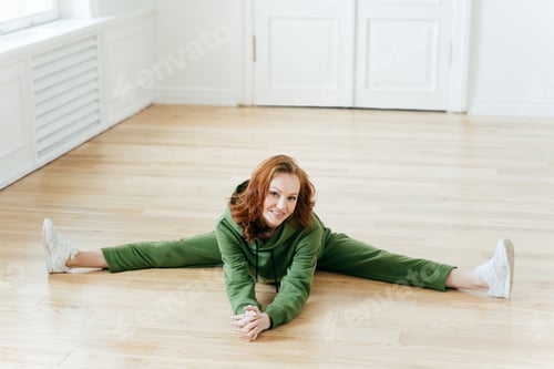 Preview: Woman does pilates exercises, dressed in green tracksuit, has nice flexibility, practices yoga.