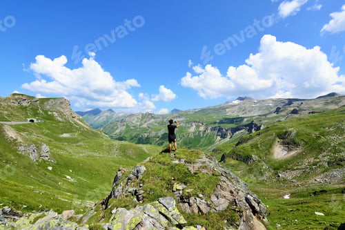 Preview: Man hiker standing on top of a mountain and enjoying the view