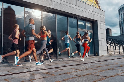 Preview: Full Length Of Young People In Sports Clothing Jogging While Exercising On The Sidewalk Outdoors
