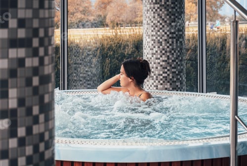 Preview: Attractive young woman relaxing in whirlpool in spa