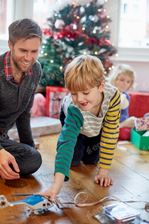 Preview: A man and two children finding and unwrapping presents on Christmas day.