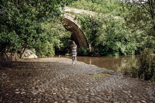 Preview: Young woman walking by a stone bridge in the forest
