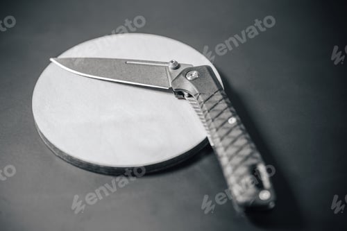 Preview: Foldable pocket knife on metal and wooden background.