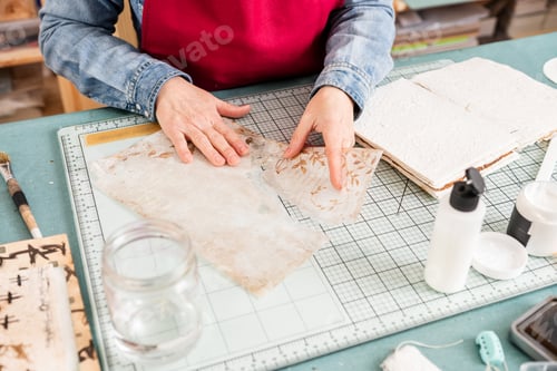 Preview: Woman Engages in Scrapbook Activity With Paper on Desk During Daytime at a Crafting Space