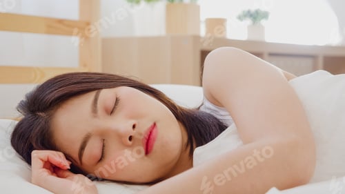 Preview: Asian woman dreaming while sleeping on bed in bedroom.