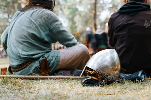 Preview: Close-up of a medieval old steel helmet with protection lying on the grass near the knights resting