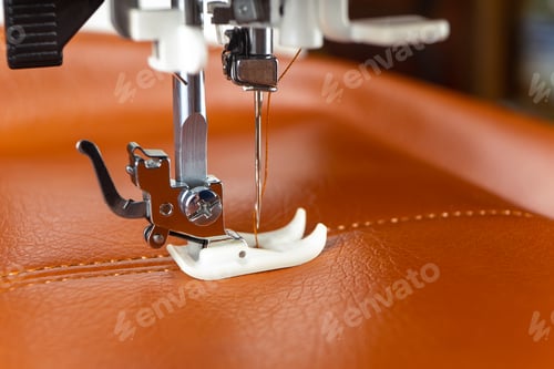 Preview: Modern sewing machine presser foot with a needle sews brown leather