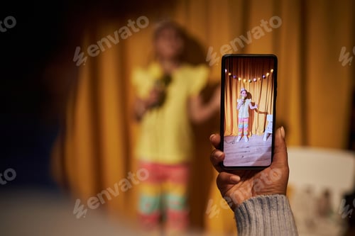 Preview: Parent Holding Smartphone and Filming Little Girl In Talent Show