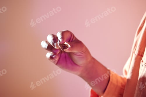 Preview: cropped view of african american man holding cigarette paper with tabacco, bad habit concept