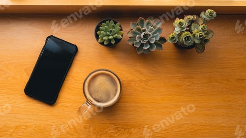 Preview: Coffee in a mug on a wooden table with notebooks and small plants.