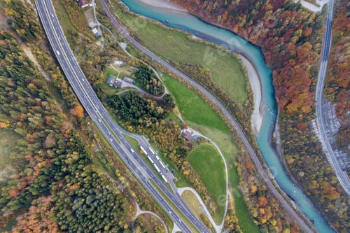 Preview: Top dawn aerial view of freeway speed road between yellow autumn forest trees and blue river