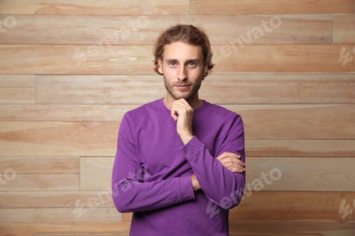 Preview: Handsome young man in warm sweater on wooden background