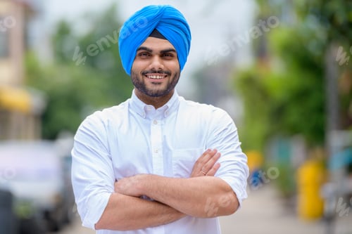 Preview: Happy young bearded Indian Sikh man smiling outdoors