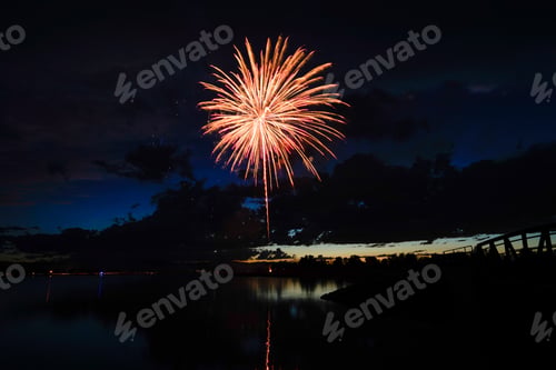 Preview: a fireworks display at night near a lake with lights in the dark