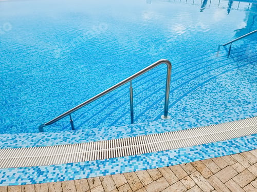 Preview: Beautiful pool with a Metal Handrails Descent and blue water at sunset. Swimming and summer rest