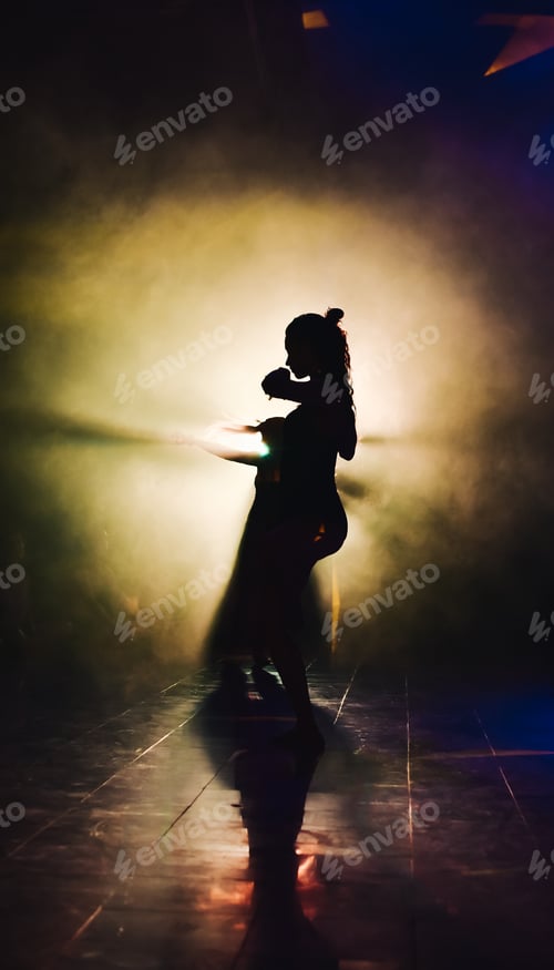 Preview: silhouette of a woman dancing between lights and smoke