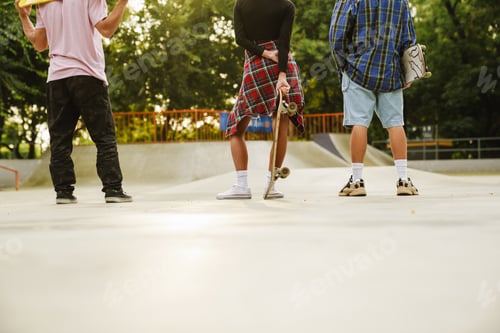 Preview: White teenagers holding skateboards while spending time at skate park
