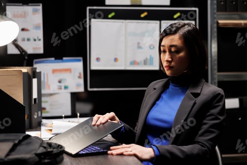 Preview: Focused Woman Closing Laptop at Her Desk