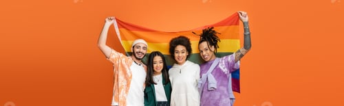 Preview: happy multiethnic friends in trendy clothes holding lgbt flag isolated on orange, banner