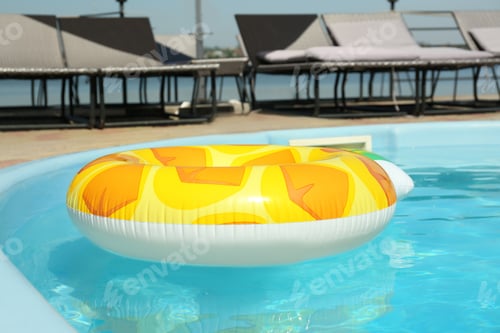 Preview: Colorful inflatable ring floating in swimming pool on sunny day, outdoors